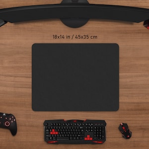 May include: A black rectangular gaming mouse pad, 18 x 14 inches, is surrounded by gaming accessories. A black keyboard with red accents, a mouse, a controller, and headphones are visible. The setup is on a wooden surface.