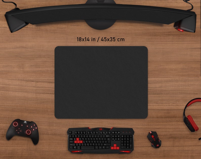 May include: A black rectangular gaming mouse pad, 18 x 14 inches, is surrounded by gaming accessories. A black keyboard with red accents, a mouse, a controller, and headphones are visible. The setup is on a wooden surface.