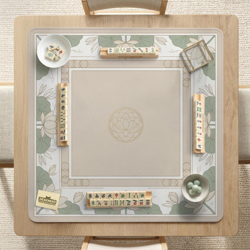 May include: A square wooden Mahjong table with a beige playing surface featuring a lotus flower design and green accents. The table includes wooden tile racks, dice, and a small bowl of green game pieces. The brand name "DESKNEKO" is visible.