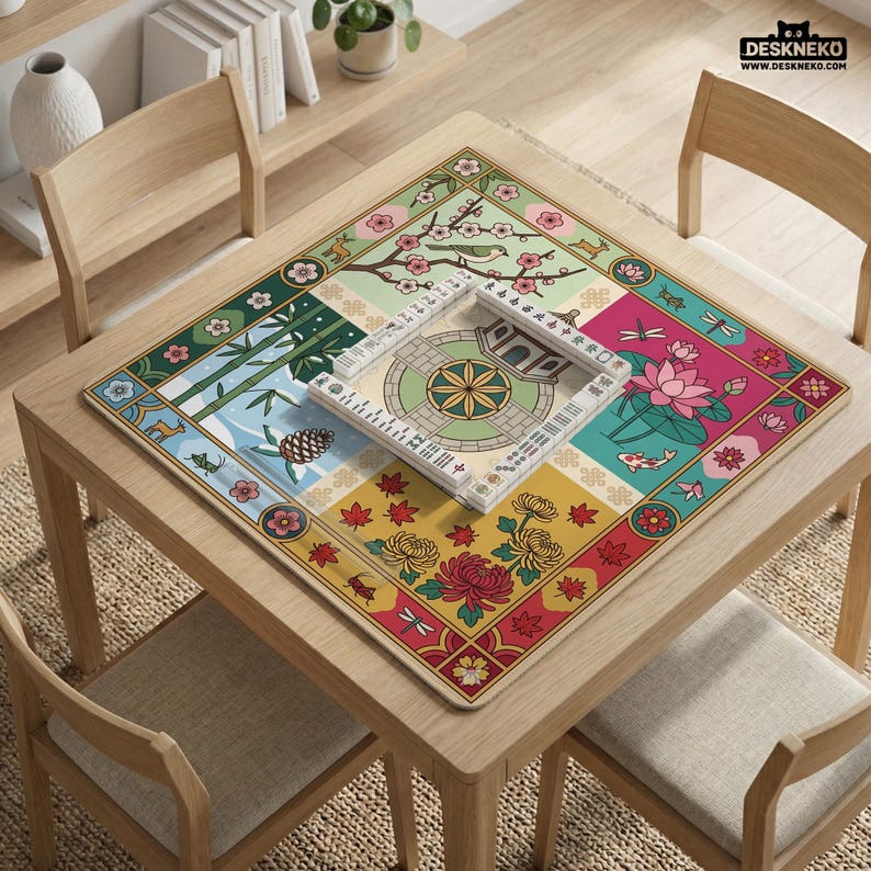 May include: A square, wooden table with a colorful, patterned mat featuring floral and nature-themed designs. A game board with tiles is centered on the mat. The table is surrounded by four wooden chairs.