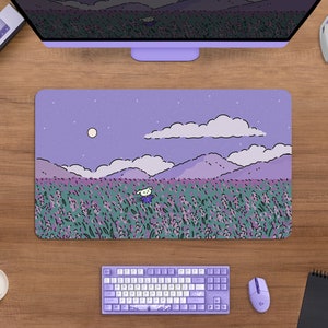 May include: A rectangular purple mousepad with a whimsical illustration of a field of lavender under a starry night sky. A cartoon character is in the field. The mousepad is surrounded by a keyboard, mouse, and other computer accessories.