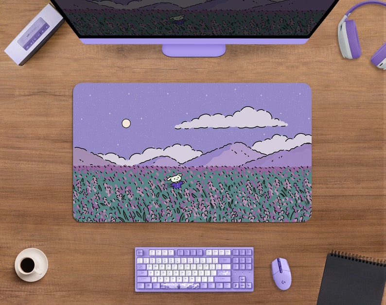 May include: A rectangular purple mousepad with a whimsical illustration of a field of lavender under a starry night sky. A cartoon character is in the field. The mousepad is surrounded by a keyboard, mouse, and other computer accessories.