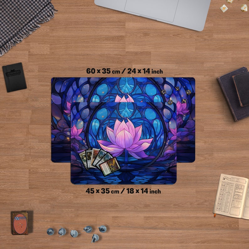 May include: Gaming playmat featuring a stained-glass lotus flower design in shades of blue and purple. The mat measures 24 x 14 inches and 18 x 14 inches. Includes a deck of cards and dice. The text "DESKNEKO" is visible.
