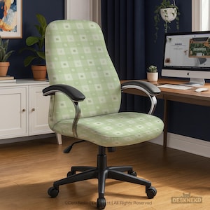 May include: A light green office chair with a patterned design of squares and cat faces. The chair has black armrests and a black base with wheels. The chair is in a home office setting.