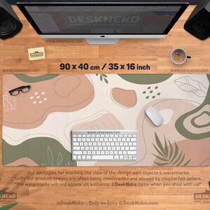 Puede incluir: Alfombrilla de escritorio con dise&ntilde;o abstracto en beige, verde y marr&oacute;n, mide 90 x 40 cm. La alfombrilla tiene un teclado, un rat&oacute;n y gafas. El texto "DeskNeko" y direcciones web son visibles.