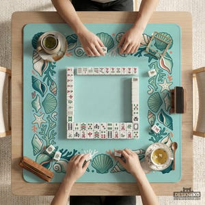 May include: A Mahjong game in play, viewed from above. The game is set on a light blue mat decorated with seashells and coral. White tiles are arranged in a square, with players' hands visible. Teacups and wooden accessories are also present.