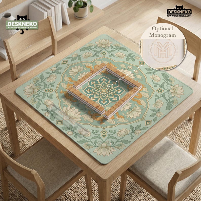 May include: A square desk mat featuring a light green background with a symmetrical floral lotus pattern in cream and dark green. A wooden frame sits in the center. A circular inset shows an optional monogram with the letters MY in a gold line design.