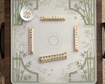 Könnte beinhalten: Ein Mahjong-Spielset auf einem quadratischen Tisch. Das Spielbrett hat eine hellgraue Oberfläche mit Bambus- und Wassermuster. Das Set enthält Spielsteine, Würfel und eine kleine weiße Schale. Der Tisch ist dunkelbraun.