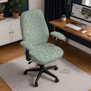 May include: An office chair with a light green fabric featuring a white leaf pattern. The chair has a black base with five wheels and adjustable armrests. The chair is on a light gray rug.