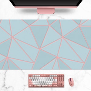 Può includere: Un ampio tappetino per mouse rettangolare con un design geometrico. Il tappetino presenta uno sfondo azzurro con un motivo di triangoli interconnessi delineati in rosa. Sono visibili anche una tastiera, un mouse e un monitor rosa.