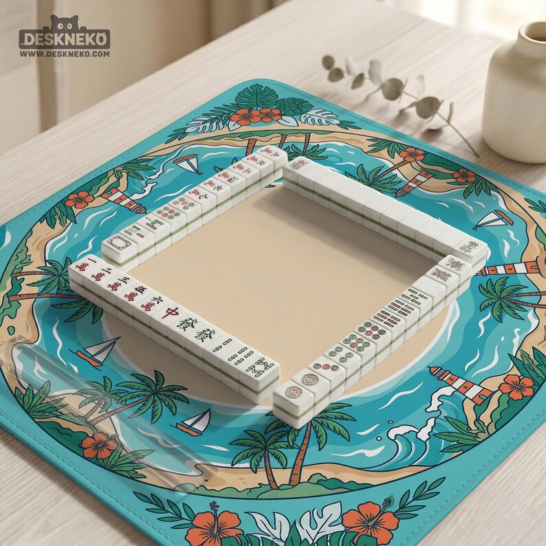 May include: A Mahjong set displayed on a tropical-themed mat. The mat depicts a beach scene with palm trees, sailboats, and a lighthouse. The tiles are white with black and red markings. The mat is approximately 38 cm square.