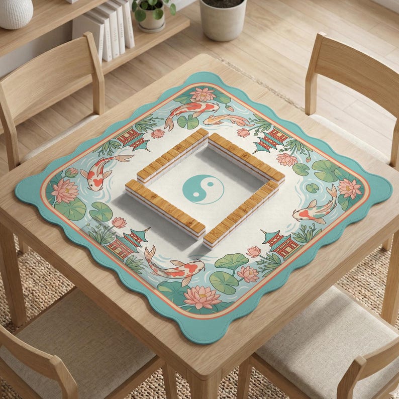 May include: A square table with a decorative mat featuring a koi pond design. The mat has a scalloped edge and a light blue border. The koi pond design includes koi fish, lotus flowers, and pagodas. Wooden game pieces are arranged on the mat.