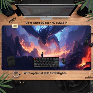 Op de afbeelding: Een grote rechthoekige bureaumat met een fantasiedraakscène en een persoon ervoor. De mat meet tot 120 x 60 cm. De mat heeft de tekst "With optional LED/RGB lights" en het websiteadres "www.DESKNEKO.COM".