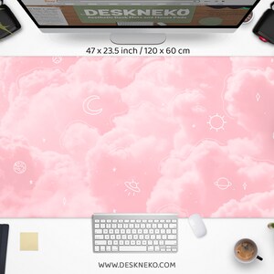 May include: A large pink desk mat with a cloud design and white celestial illustrations, including a moon, stars, and planets. The mat measures 47 x 23.5 inches. The website address www.deskneko.com is printed at the bottom.