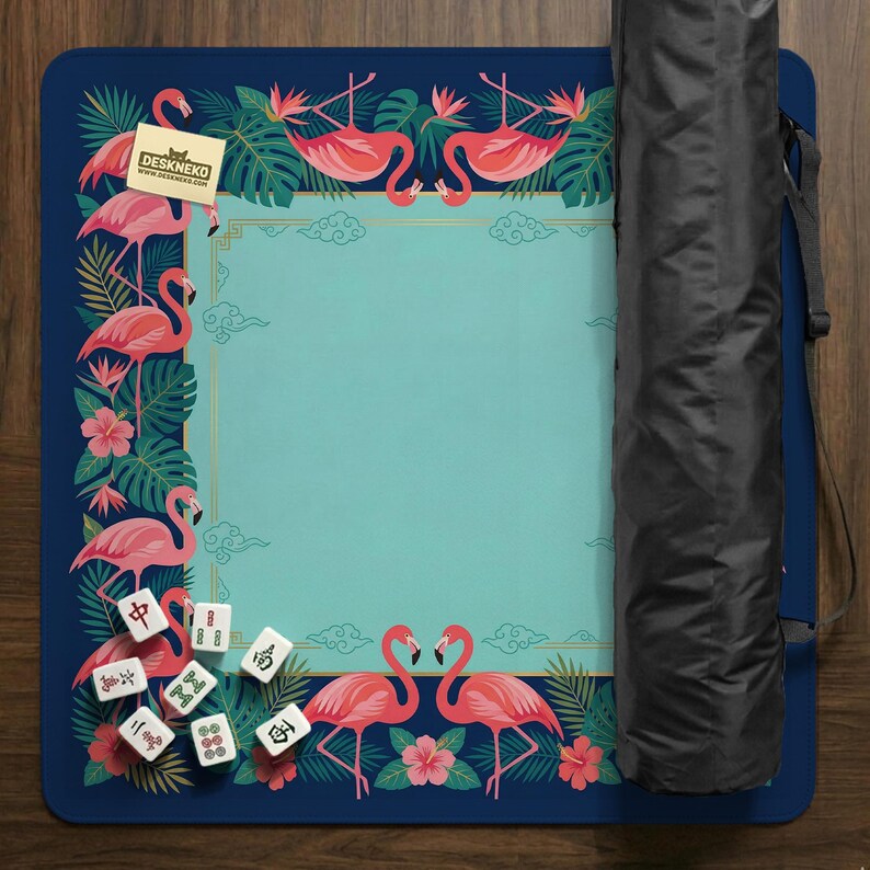 May include: A blue and teal mahjong mat with a flamingo design. The mat features pink flamingos, tropical flowers, and Chinese characters. The mat has a teal center with a decorative border and the text "DESKNEKO". A black carrying case is on the right.
