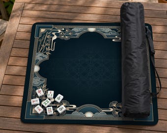 May include: A dark blue Mahjong mat with an Asian-inspired design featuring bamboo, clouds, and ginkgo leaves. The mat has a decorative border and is accompanied by a black carrying case. Several Mahjong tiles are visible.