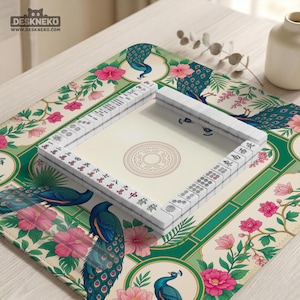 May include: A square mahjong mat featuring a cream background with a repeating pattern of blue and green peacocks, pink hibiscus flowers, and green foliage. A set of white mahjong tiles is arranged in a square frame on the mat's center.