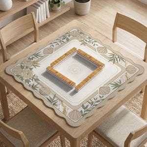 May include: A square wooden table with a decorative mat featuring floral and seashell designs. The mat surrounds a square area with a floral design, and four wooden game pieces are arranged in a square. The table is surrounded by wooden chairs.