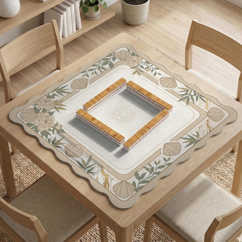 May include: A square wooden table with a decorative mat featuring floral and seashell designs. The mat surrounds a square area with a floral design, and four wooden game pieces are arranged in a square. The table is surrounded by wooden chairs.
