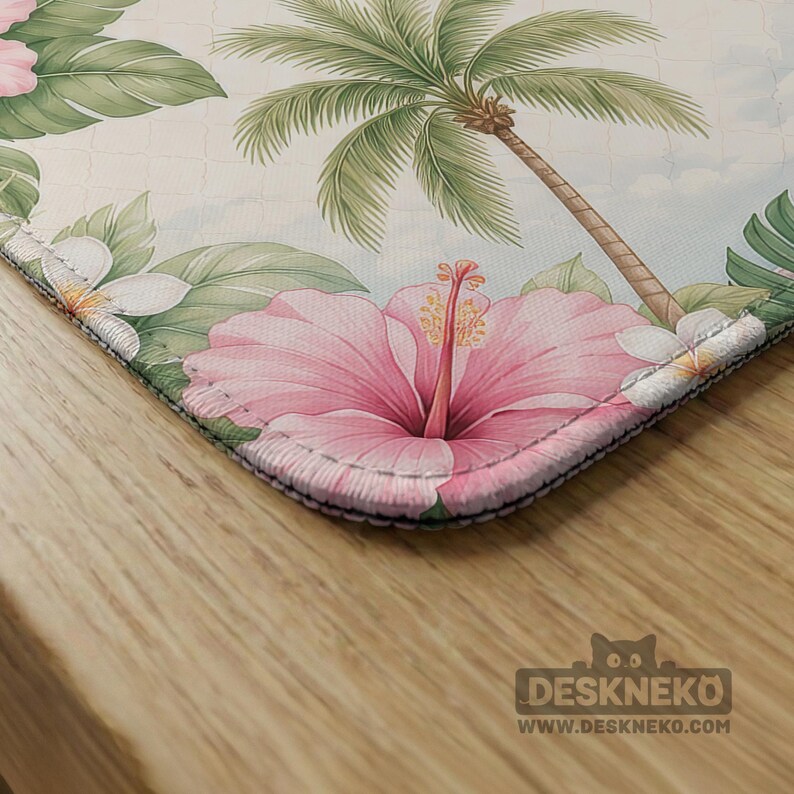 May include: A rectangular desk mat featuring a tropical pattern with large pink hibiscus flowers, green palm leaves, and white plumeria blossoms against a light background. The mat has stitched edges and a logo in the corner reading DESKNEKO.