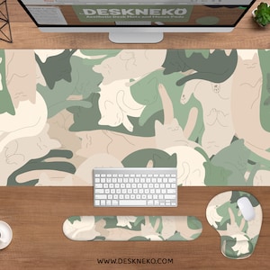 May include: Aesthetic desk mat and accessories featuring a repeating pattern of stylized cats in shades of green, beige, and cream. Includes a large rectangular mat, wrist rest, and mouse pad. The website address www.deskneko.com is visible.