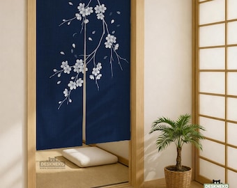 May include: A dark blue noren curtain featuring a white cherry blossom branch design. The fabric is split down the center, revealing a white floor cushion inside a room. The text DESKNEKO is printed in the bottom left and bottom right corners.
