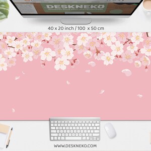 May include: Aesthetic desk mat and mouse pad with a pink background and a floral cherry blossom design. The mat measures 40 x 20 inches (100 x 50 cm). The website address www.deskneko.com is printed at the bottom.