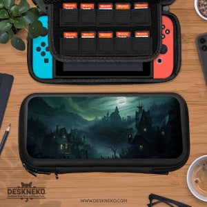 May include: Black carrying case for a game console, featuring a spooky landscape design. The case is open, revealing the console and game cartridges. The console has blue and red controllers. The text "DESKNEKO" and website address are visible.