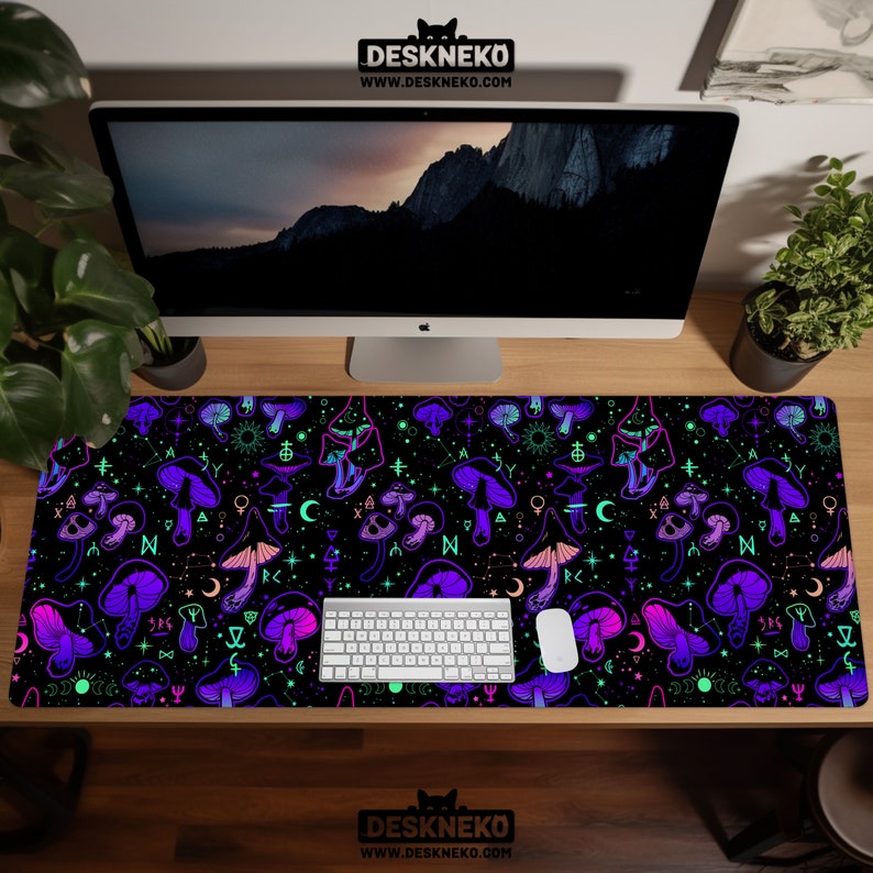 May include: A black desk mat featuring a vibrant pattern of purple and pink mushrooms, moons, stars, and other mystical symbols. The mat has the text "DESKNEKO" and "WWW.DESKNEKO.COM" printed on it. A white keyboard and mouse are on the mat.