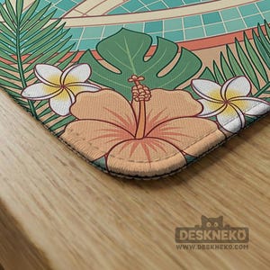 May include: A rectangular desk mat featuring a tropical floral design. The mat showcases a large orange hibiscus flower, white plumeria flowers, and green leaves. The background includes a pool design with teal tiles and a beige border. The Deskneko logo is visible.