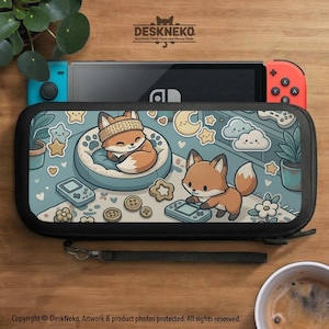 May include: A black carrying case for a gaming console featuring a light blue illustration of two foxes, one sleeping in a bed and one playing with a handheld game, surrounded by stars, clouds, moons, flowers, and buttons with a wrist strap.