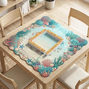 May include: A square table setting featuring a marine-themed design. The placemat showcases coral, seashells, and starfish in shades of blue, pink, and green. A wooden frame sits in the center, creating a visual focal point.