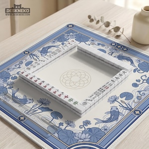 May include: A Mahjong set with white tiles and red and green markings is arranged on a blue and white floral patterned mat. The mat features koi fish and lotus flowers. The brand name "DESKNEKO" is visible in the top left corner.