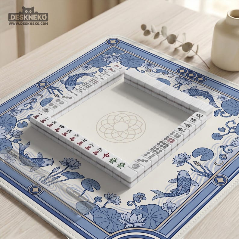 May include: A Mahjong set with white tiles and red and green markings is arranged on a blue and white floral patterned mat. The mat features koi fish and lotus flowers. The brand name "DESKNEKO" is visible in the top left corner.