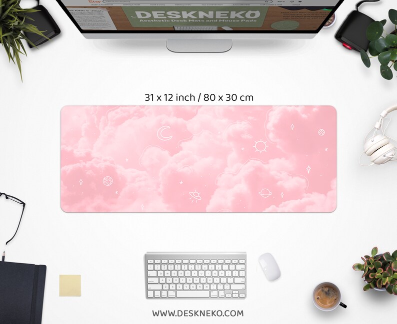 May include: Aesthetic desk mat with a pink cloud design and white celestial illustrations. The mat measures 31 x 12 inches. The website address www.deskneko.com is printed at the bottom. The mat is surrounded by a keyboard, mouse, and other desk accessories.