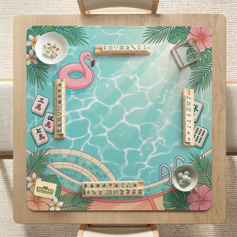 May include: A square wooden mahjong table with a tropical pool-themed mat. The mat features a pink flamingo float, water ripples, and floral accents. Mahjong tiles and accessories are arranged on the mat, ready for play.
