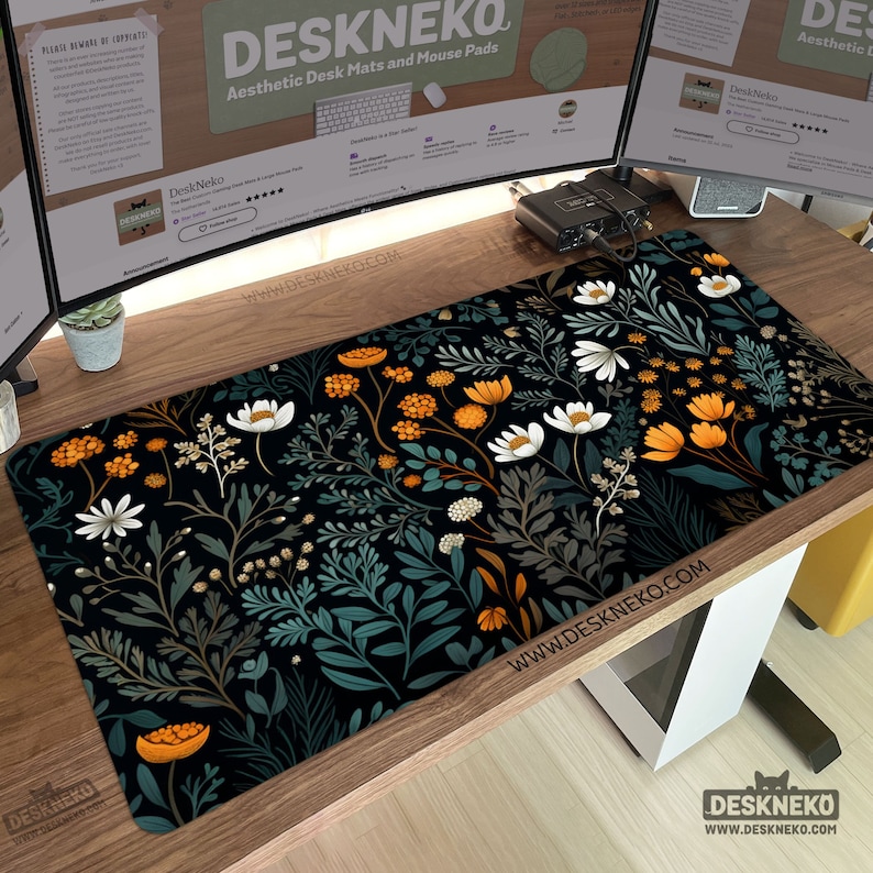 May include: A rectangular desk mat with a floral pattern featuring white, orange, and teal flowers and foliage on a black background. The mat has the text "DESKNEKO" and "Aesthetic Desk Mats and Mouse Pads".