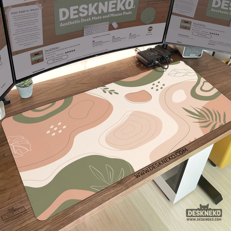 Puede incluir: Alfombrilla de escritorio est&eacute;tica con fondo crema y formas abstractas en tonos verdes y melocot&oacute;n. La alfombrilla presenta dise&ntilde;os de hojas y l&iacute;neas. El texto "DESKNEKO" y "WWW.DESKNEKO.COM" son visibles.