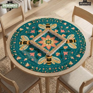 May include: A round desk mat featuring a teal background with a repeating pattern of bees and pink flowers. A square wooden frame is placed in the center of the mat. The text DESKNEKO is visible in the top left and top right corners of the image.