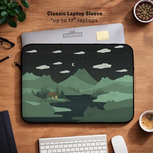 May include: Classic laptop sleeve with a nature-themed design. The sleeve features a dark green landscape with mountains, a river, and a cabin under a starry night sky. Fits up to 17-inch laptops. The text "Classic Laptop Sleeve" is printed at the top.