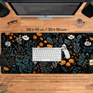 May include: A black desk mat with a floral design, measuring 35 x 16 inches. The pattern features white, orange, and teal flowers and foliage. A white keyboard and mouse are on the mat. The text "DeskNeko" is visible.