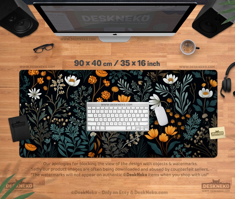 May include: A black desk mat with a floral design, measuring 35 x 16 inches. The pattern features white, orange, and teal flowers and foliage. A white keyboard and mouse are on the mat. The text "DeskNeko" is visible.