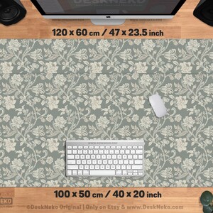 Puede incluir: Un juego de alfombrilla de escritorio y almohadilla para teclado con un dise&ntilde;o floral. La alfombrilla mide 120 x 60 cm, y la almohadilla 100 x 50 cm. El dise&ntilde;o presenta flores blancas sobre un fondo verde apagado. Un rat&oacute;n y un teclado blancos est&aacute;n sobre la alfombrilla.