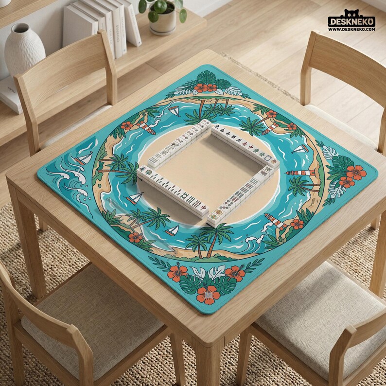 May include: A square wooden table with a turquoise mat featuring a tropical island design. The mat has palm trees, sailboats, and a lighthouse. A Mahjong set is placed on the mat. The table is surrounded by wooden chairs.
