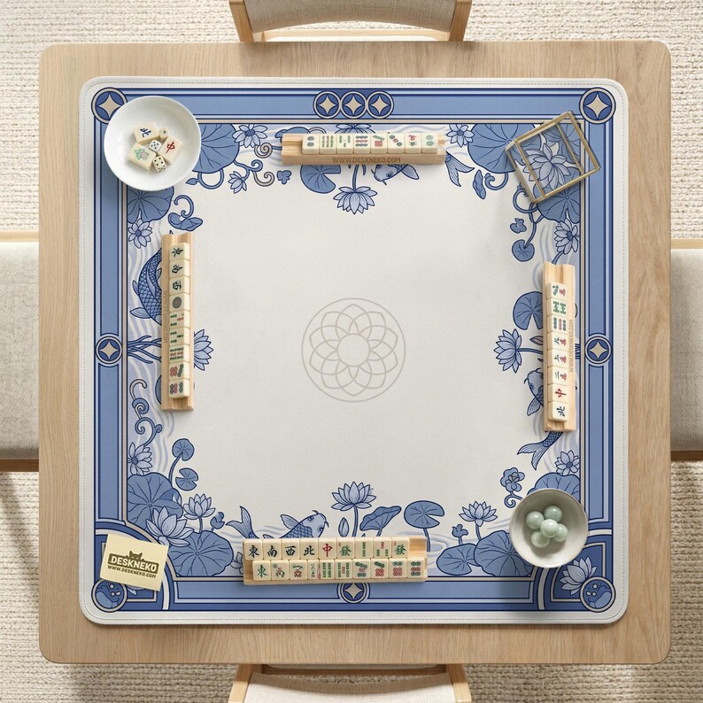 May include: A square mahjong table with a blue and white floral design. The table is set with tiles, dice, and small bowls. The table has a wooden frame and is set on a light-colored rug. The logo "DESKNEKO" is visible.