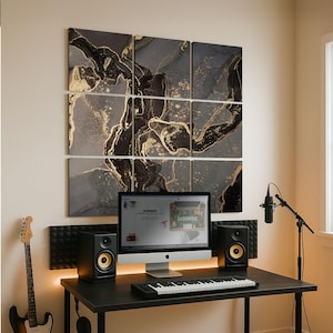 Puede incluir: Una configuración de estudio en casa con un escritorio negro, computadora, teclado y altavoces. Encima del escritorio hay una obra de arte abstracta de nueve paneles con detalles dorados y negros. También hay una guitarra y un micrófono.