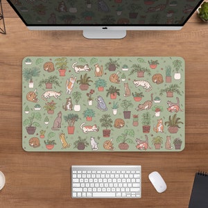Puede incluir: Alfombrilla de rat&oacute;n rectangular con fondo verde claro. Presenta un patr&oacute;n de plantas en macetas e ilustraciones de varios gatos. Los gatos est&aacute;n en diferentes poses y las plantas en macetas de terracota.