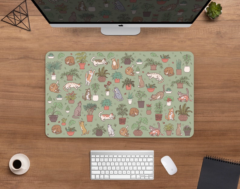 Puede incluir: Alfombrilla de rat&oacute;n rectangular con fondo verde claro. Presenta un patr&oacute;n de plantas en macetas e ilustraciones de varios gatos. Los gatos est&aacute;n en diferentes poses y las plantas en macetas de terracota.