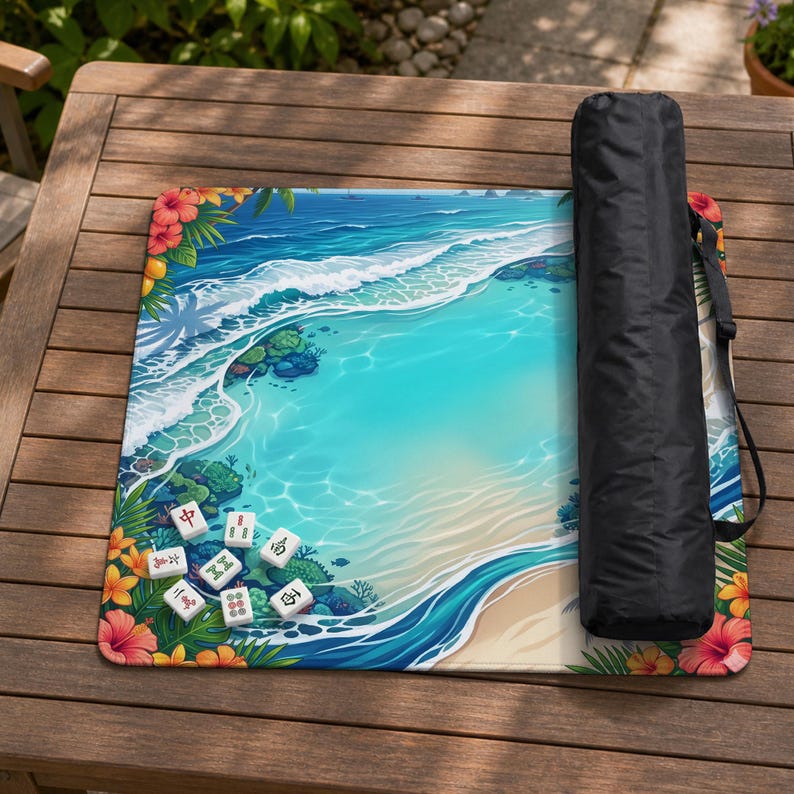 May include: A square mahjong mat featuring a vibrant tropical beach scene with turquoise water, white waves, and colorful hibiscus flowers. The mat includes a black carrying case with a shoulder strap and several white mahjong tiles.