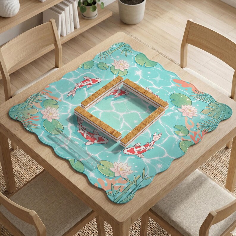May include: A square scalloped-edge table mat featuring a light blue water surface pattern with red and white koi fish, pink lotus flowers, green lily pads, and bamboo stalks, centered with a square wooden frame made of four connected slats.
